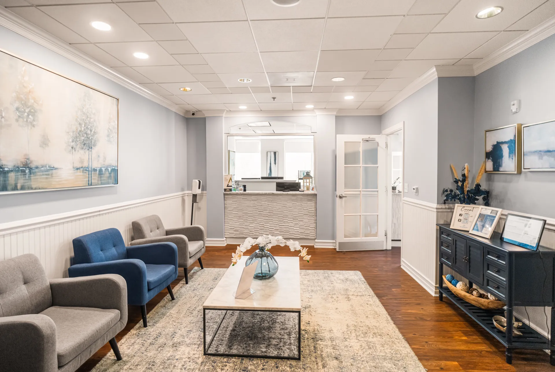 Reception waiting area with blue and grey chairs along a bright hallway — Meadowmont Dentistry in Chapel Hill, NC