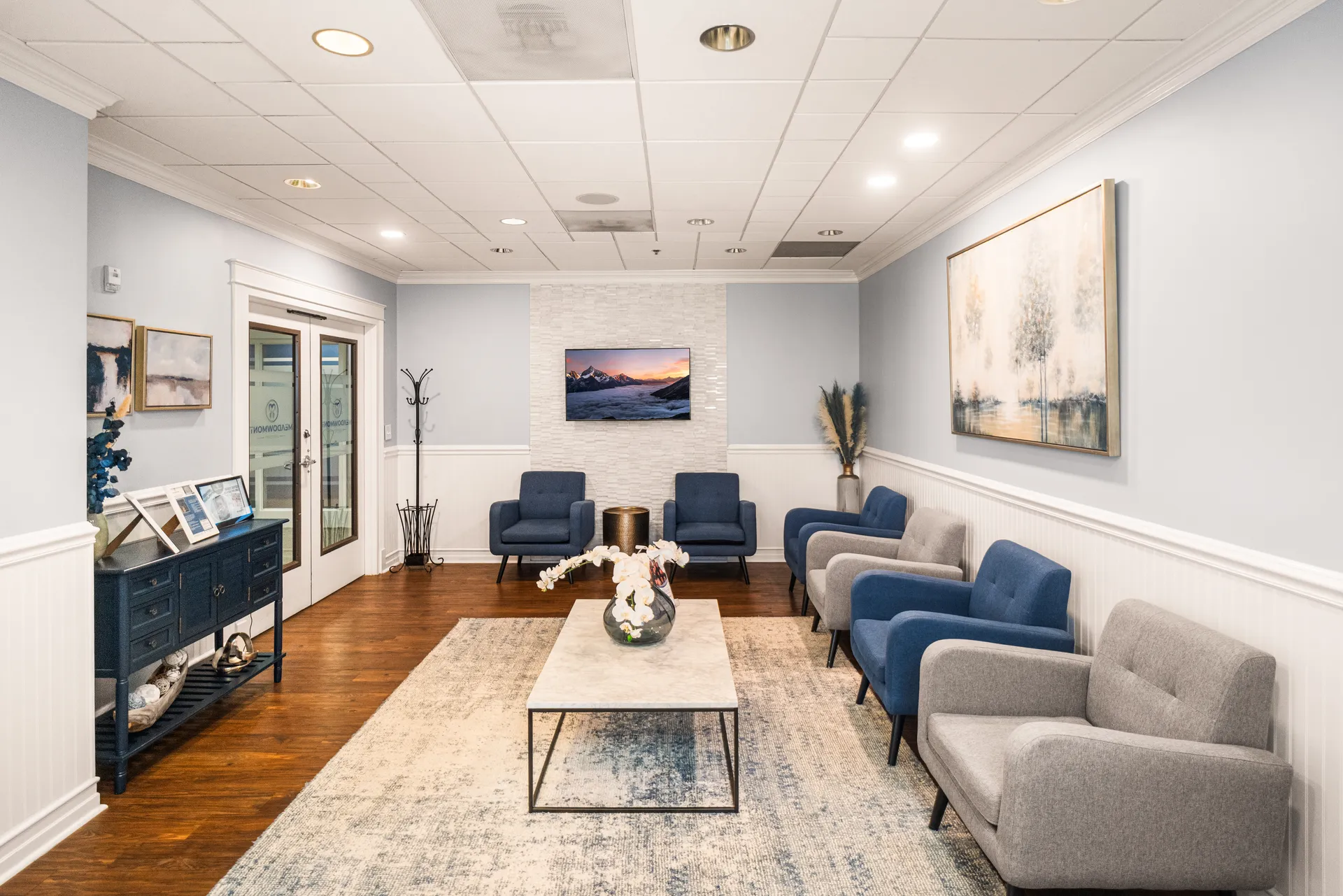 Bright waiting room with grey sofas, coffee table and coastal artwork — Meadowmont Dentistry in Chapel Hill, NC